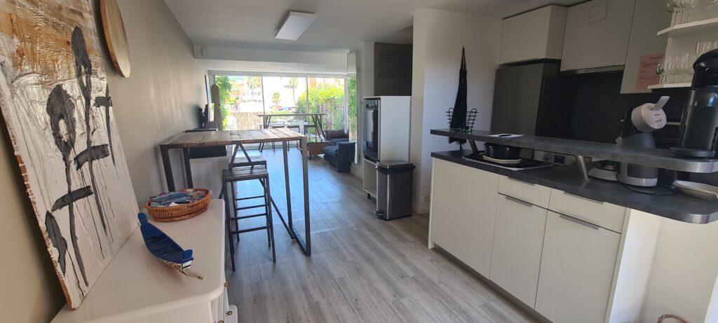 Photographie du salon de la villa, avec son grand canapé, sa télévision et ses tables bar