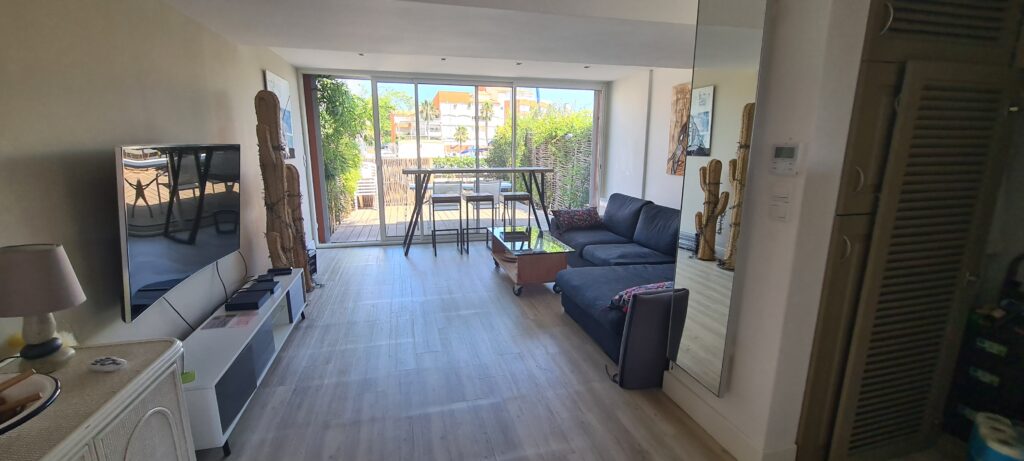 Photographie du salon de la villa, avec son grand canapé, sa télévision et ses tables bar