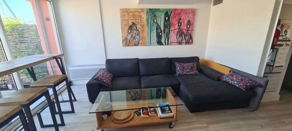 Photographie du salon de la villa, avec son grand canapé, sa télévision et ses tables bar